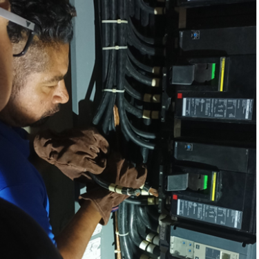 Personal técnico calificado realizando labores de mantenimiento preventivo o correctivo directamente sobre un banco de interruptores termomagnéticos principales de gran capacidad.